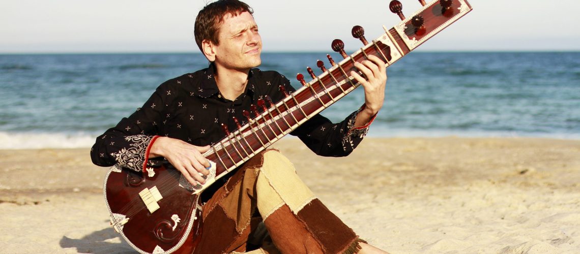 Man playing the sitar near the sea